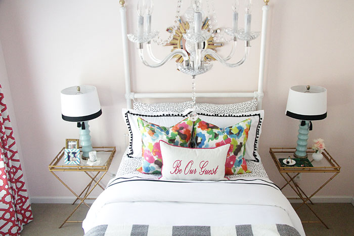 guest room decor, black and white bedding, colorful pillows, blue lamps, colorful drapes, gold sunburst mirror, chandelier 
