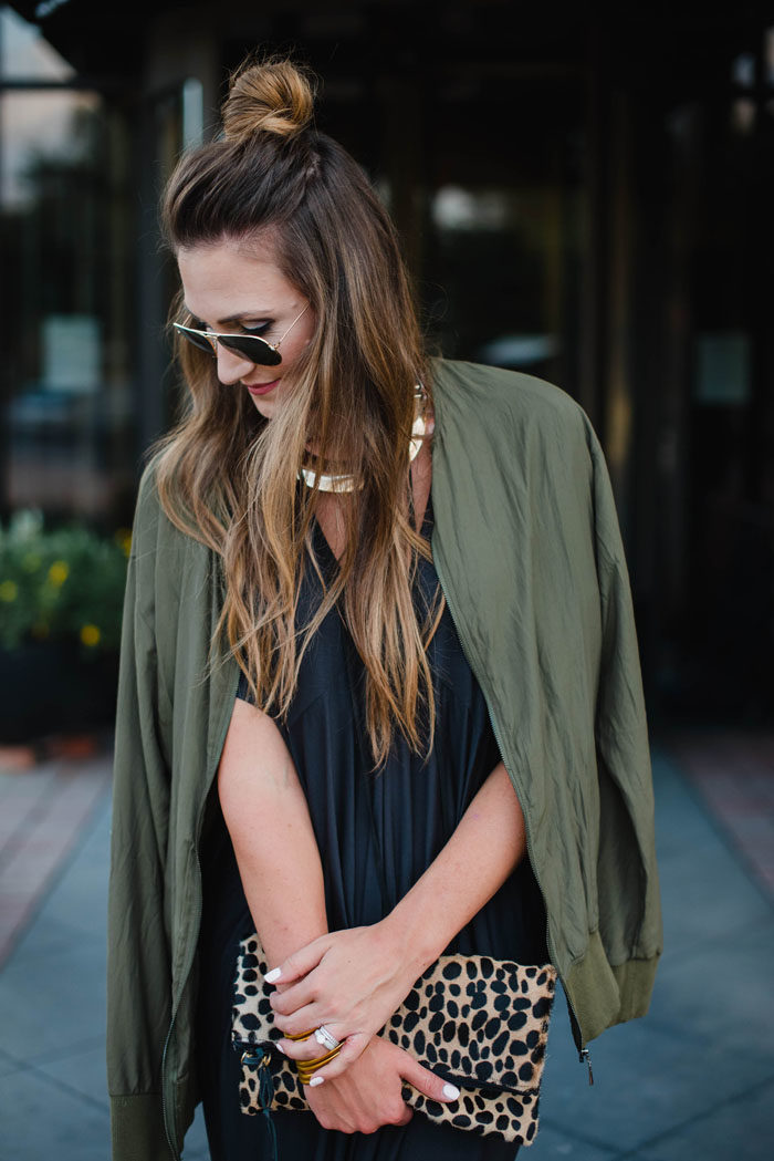 Blogger Mallory Fitzsimmons of Style Your Senses is wearing a chic black shift dress with arm green bomber jacket for a great Fall transition look.