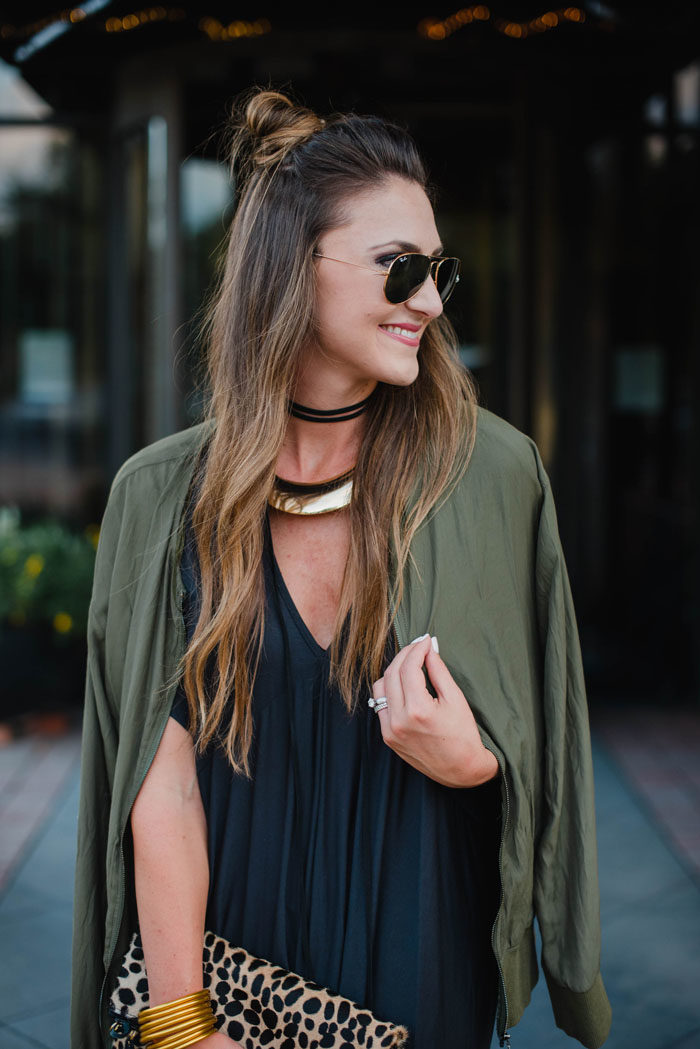 Blogger Mallory Fitzsimmons of Style Your Senses is wearing a chic black shift dress with arm green bomber jacket for a great Fall transition look.