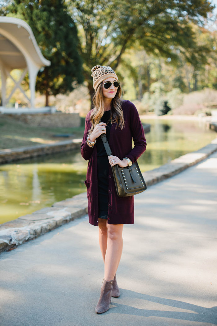 Blogger Mallory Fitzsimmons of Style Your Senses wears a black body con dress layered with a tunic cardigan and Rebecca Minkoff crossbody bag