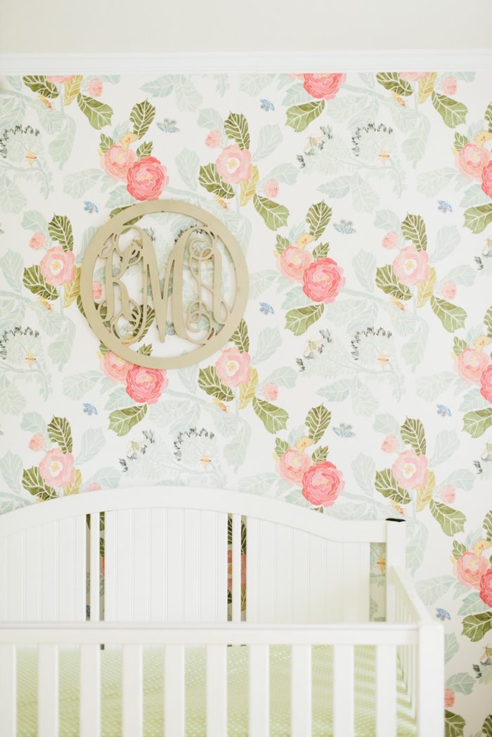 Beautiful baby girl nursery with floral wallpaper from Anthropologie and gold monogram over the crib