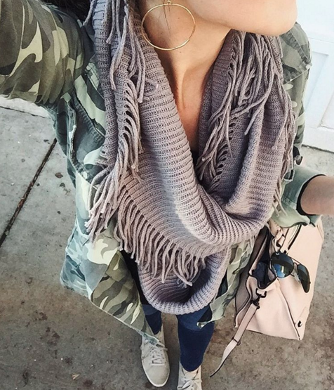 A casual outfit idea layering an infinity scarf, camo jacket and sneakers for a comfortable look that's also chic
