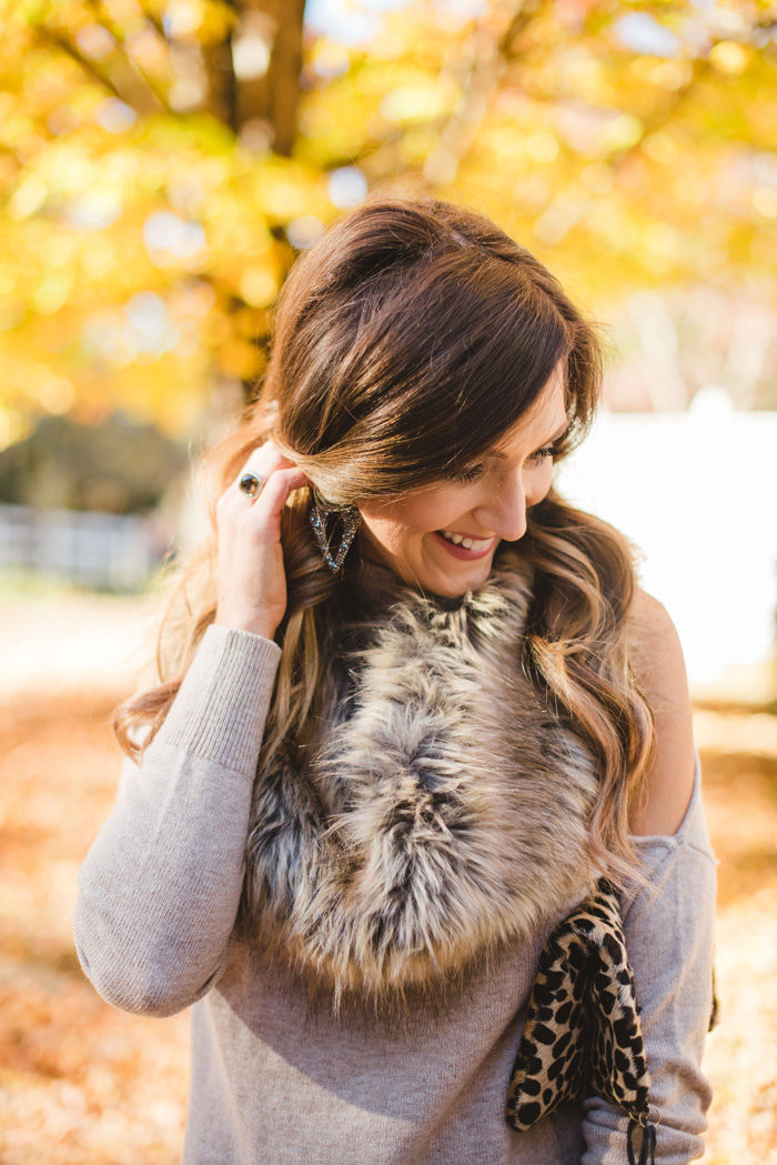 Blogger Mallory Fitzsimmons of Style Your Senses wears a cold shoulder tunic sweater with faux leather leggings, a faux fur infinity scarf and felt hat for a festive Fall and Winter look. 
