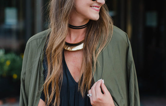 Blogger Mallory Fitzsimmons of Style Your Senses is wearing a chic black shift dress with arm green bomber jacket for a great Fall transition look.